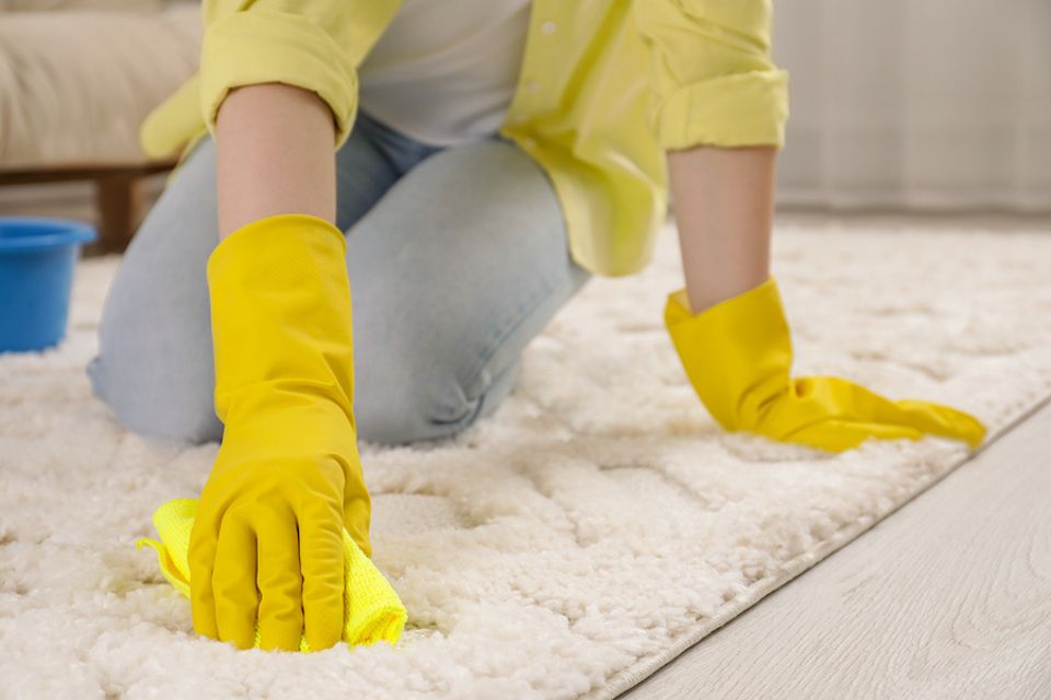 woman blotting stain from white carpet